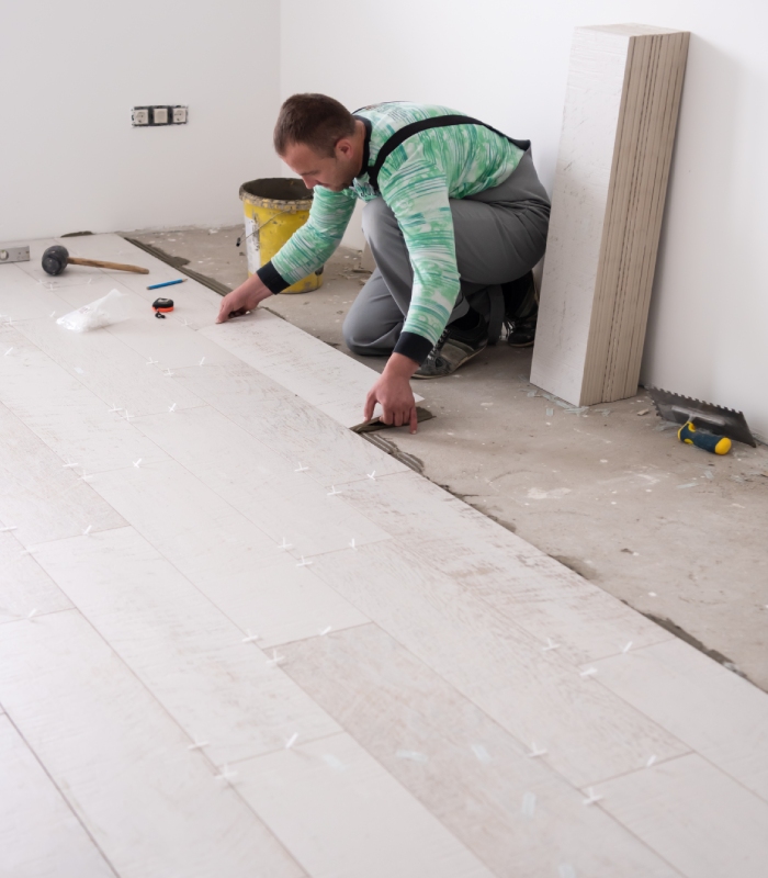 Artisan posant un revêtement de sol avec croisillons de calage dans une pièce en rénovation