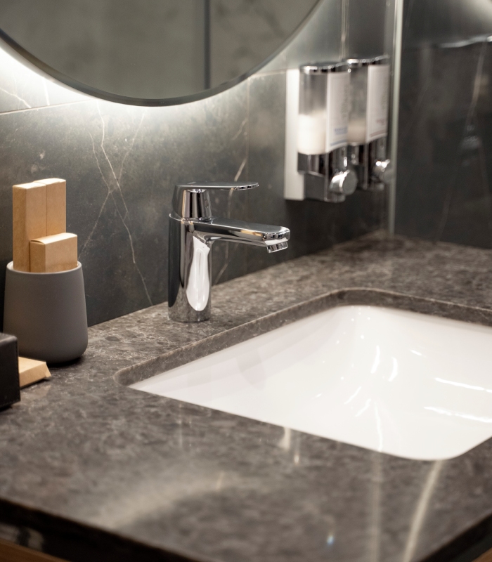 Gros plan sur un lavabo avec robinet chromé et plan de travail en pierre dans une salle de bain